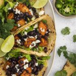 Two corn tortillas filled with seasoned tofu, black beans, lettuce, crumbled cheese, and cilantro make these Sweet Potato Black Bean Tacos irresistible. Served with lime wedges, plus sliced jalapeños and extra cilantro on the side.